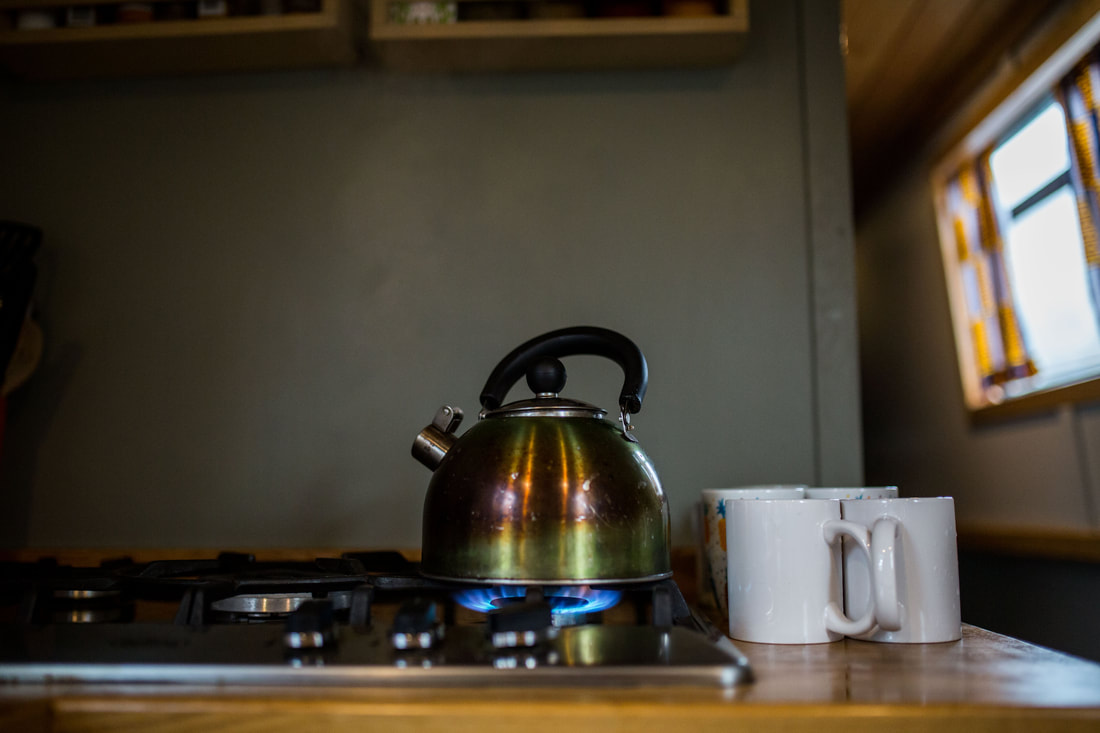 a kettle is boiling on a gas stove inside a narrowboat