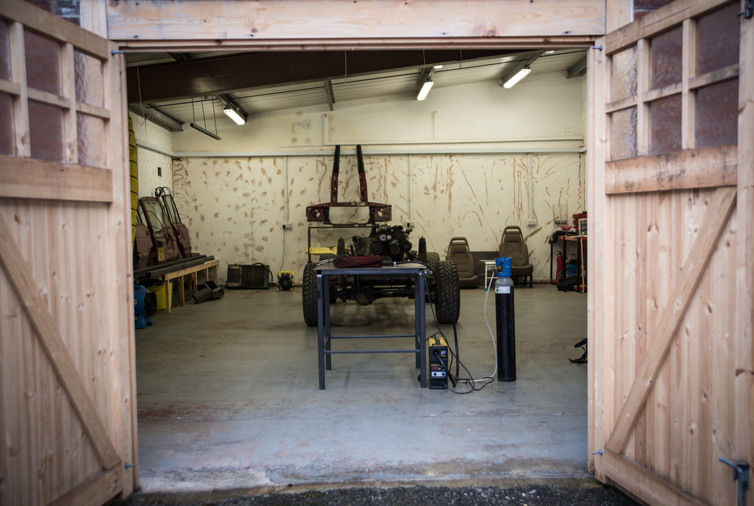 double doors open to show the interior of a workshop with a deconstructed land rover inside 